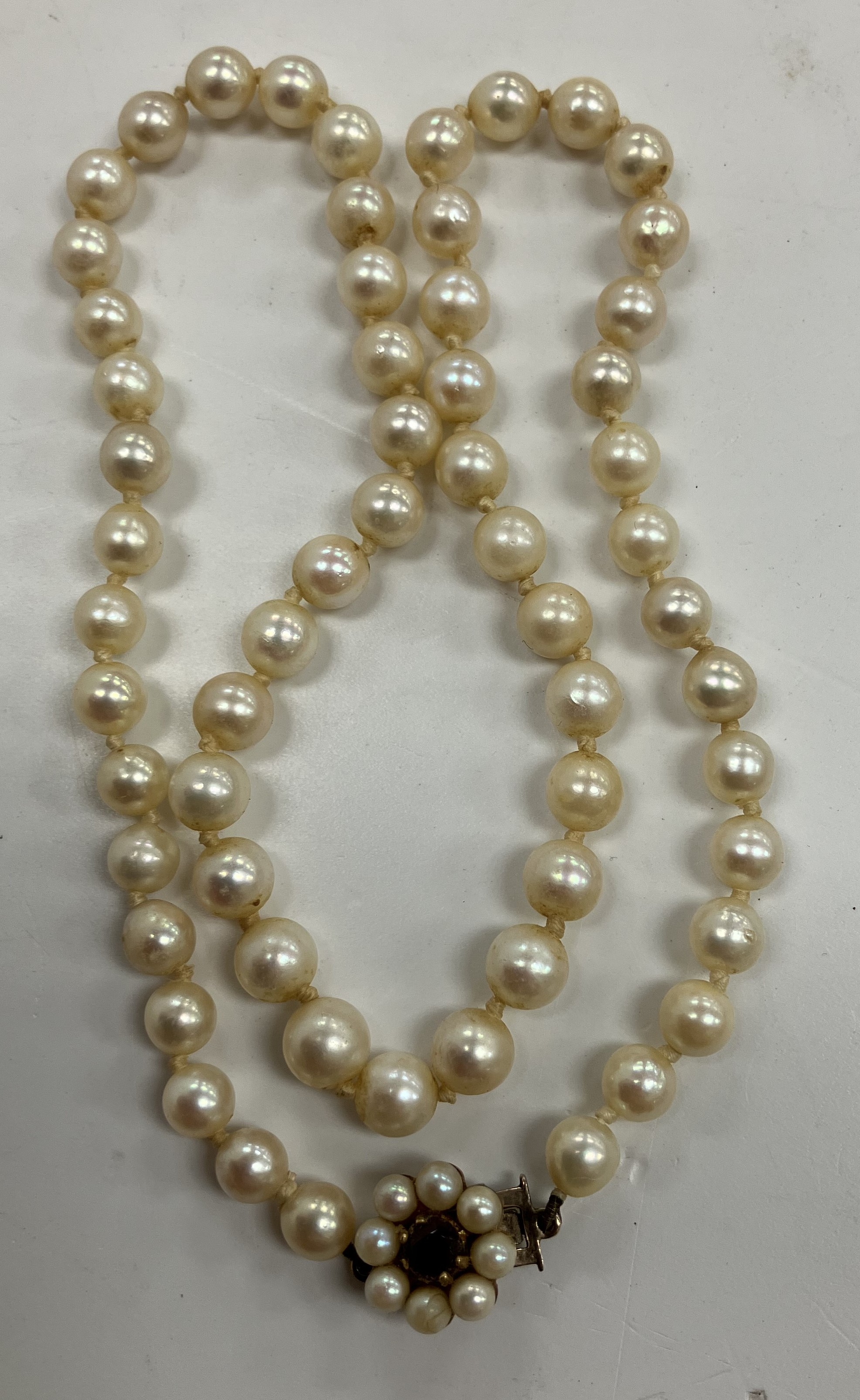 An early 20th Century cultured pearl single strand necklace with 9 carat gold mounted garnet and