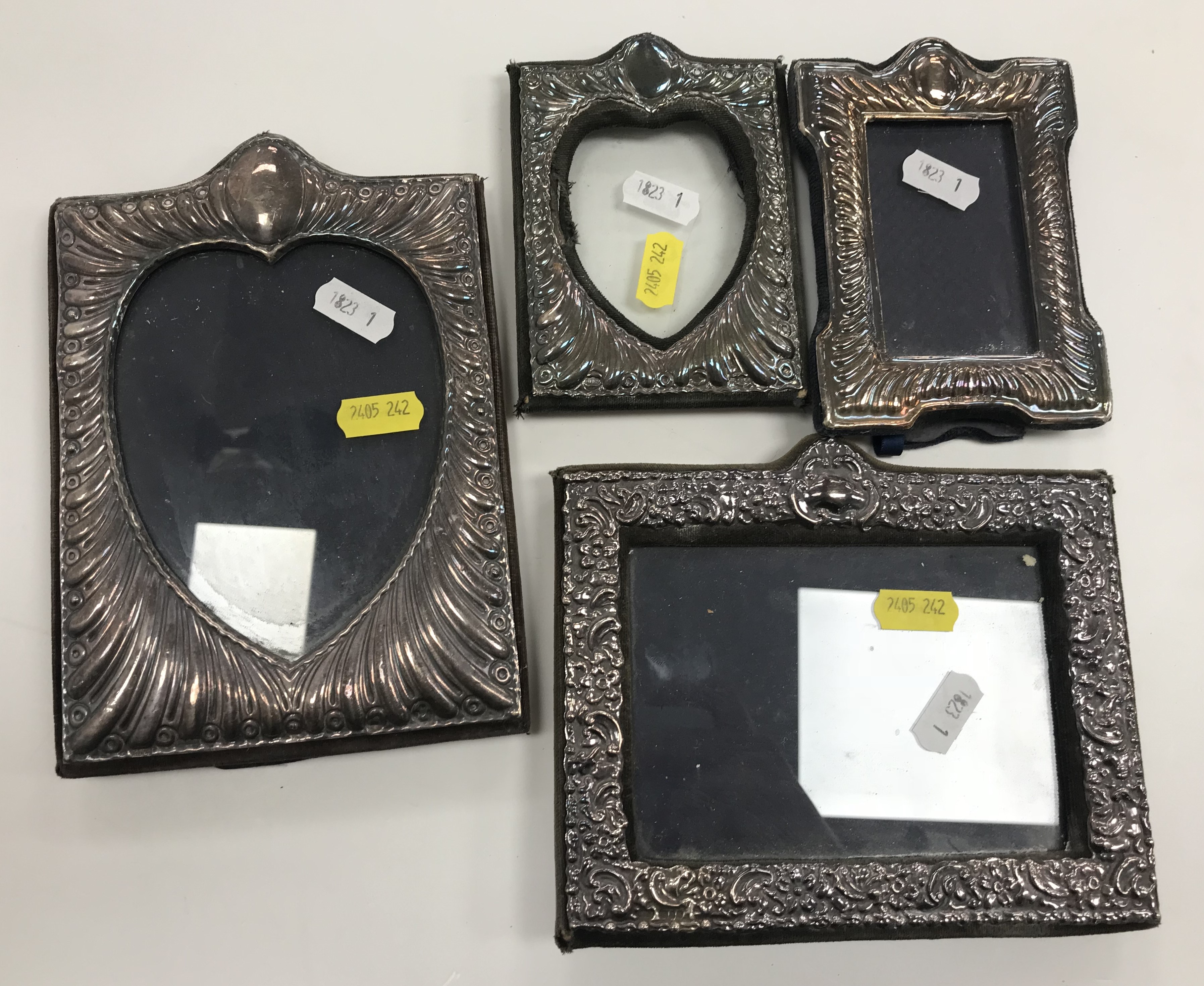 A collection of four embossed silver photo frames including a shaped rectangular frame in the Art
