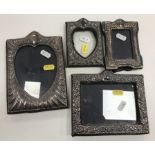 A collection of four embossed silver photo frames including a shaped rectangular frame in the Art