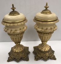 A pair of Continental cream matt glazed and gilded pottery urns and covers with gilt brass