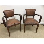 A pair of 1930s beech framed brown leather upholstered elbow chairs on square tapered slightly