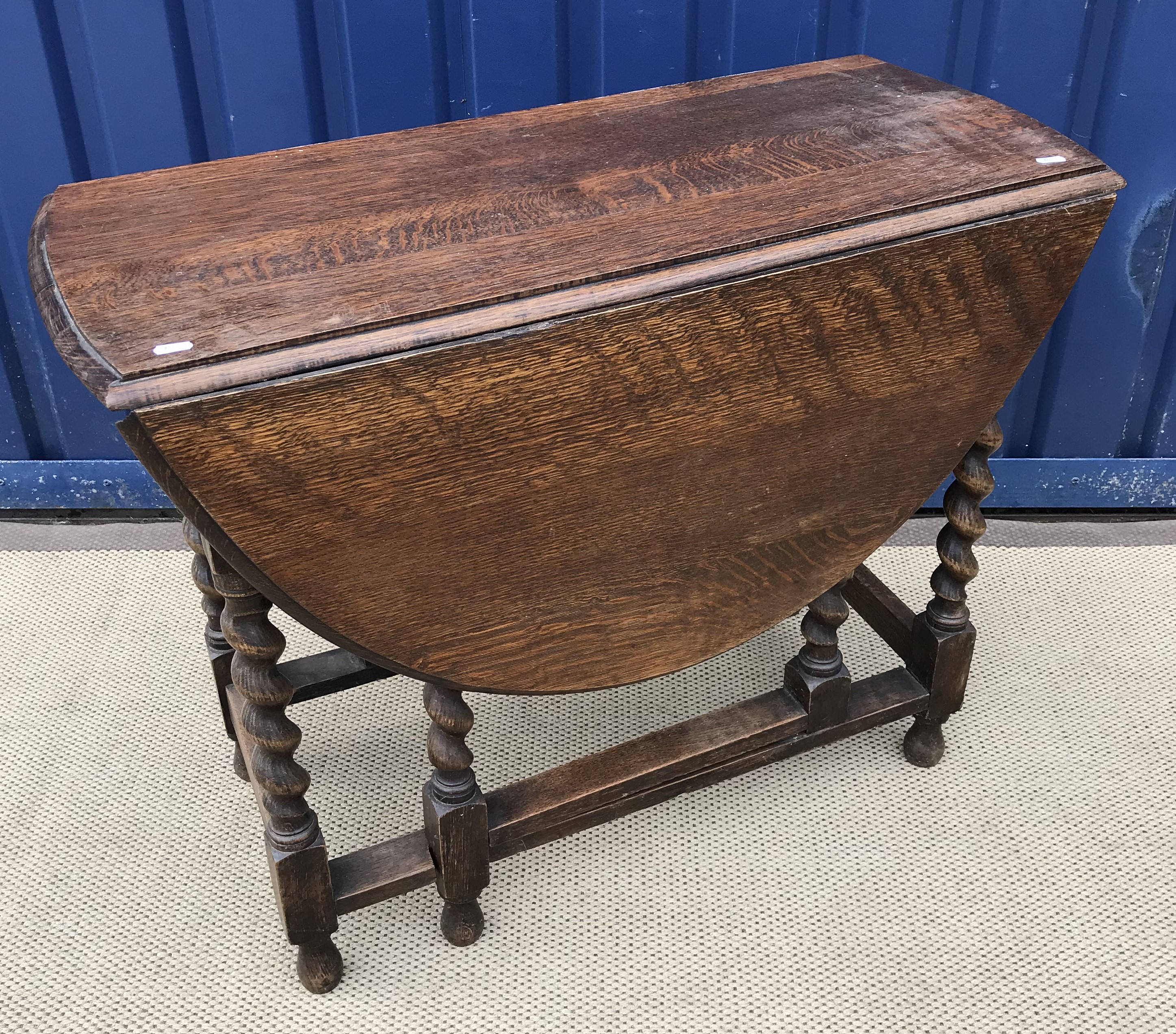 An early 20th Century oak drop leaf gate leg table raised on barley twist supports,