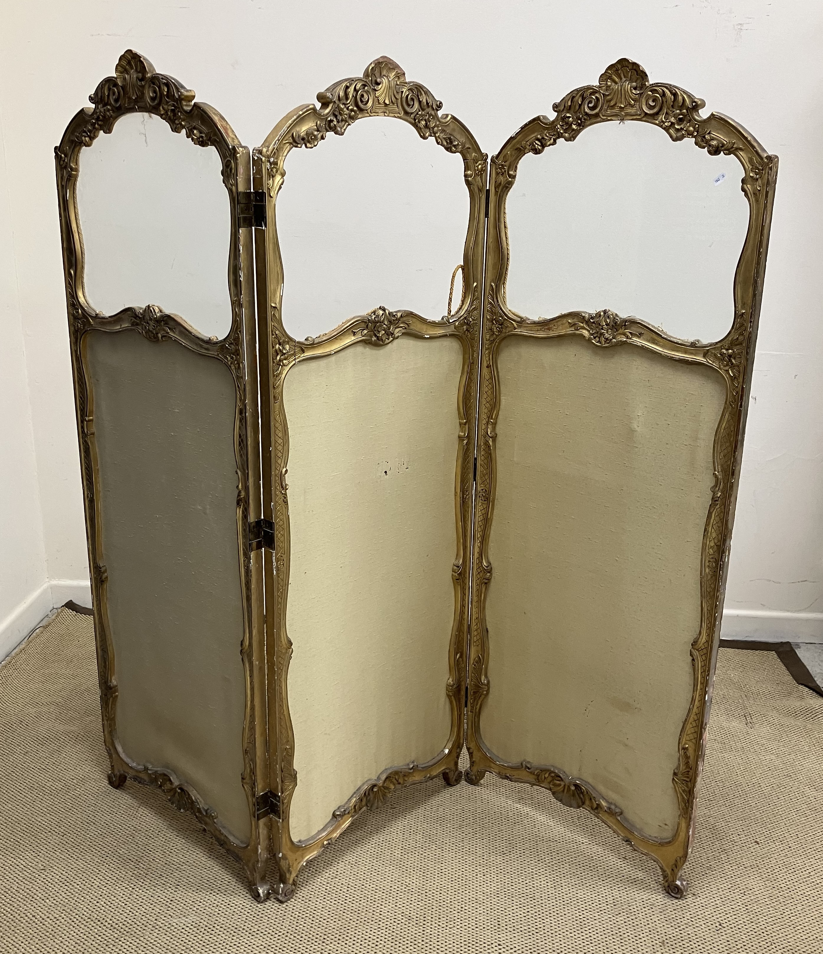 A circa 1900 carved giltwood and gesso framed dressing screen in the Louis XV taste with foliate
