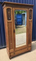 An early 20th Century oak single mirror door wardrobe with carved panelled decoration over a single