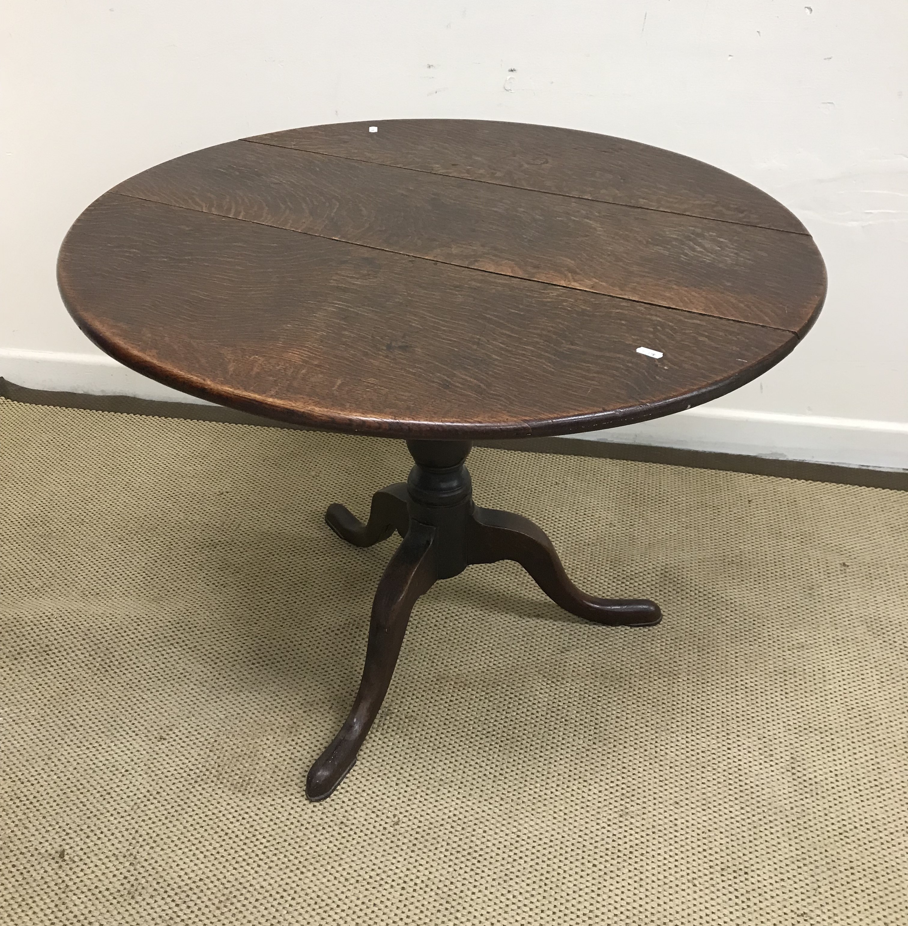 A 19th Century oak tilt top table, the circular top raised on turned pedestal to tripod base,