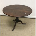 A 19th Century oak tilt top table, the circular top raised on turned pedestal to tripod base,