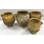 A collection of four 19th Century and later French ochre part glazed confit pots with lug handles,