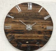 A large modern rustic wooden wall clock in the OKA manner with white metal Roman numerals and hands