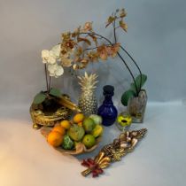 A resin pineapple, two faux orchids, a gilt jardinière stand, wooden fruit bowl with faux fruits,