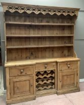 A pine kitchen dresser with pierced apron frieze above a three tier plate rack above a cupboard base
