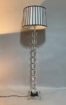 A clear glass and chrome standard lamp of ten facetted knops, on a square stepped black and clear