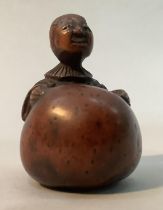A Japanese fruitwood netsuke carved as a man standing with his arms stretched around a large