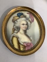 A portrait miniature, possibly of Marie Antoinette, printed and painted on a gilt metal oval