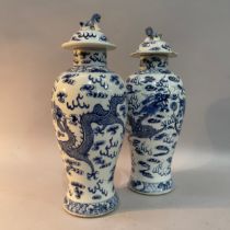 A pair of 19th century Chinese blue and white baluster vases, the domed covers with dog of Fo