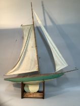 A 20th century wooden model pond yacht with rigging and sails raised on a stand, painted in teal