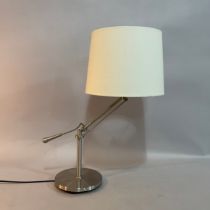 A brushed steel table lamp with adjustable rake, on circular base, cream shade, 66cm high overall