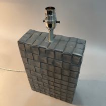 A ceramic table lamp, oblong, modelled as woven pewter-coloured leather-coloured block, silk cord
