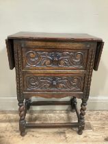 An early 20th century oak drop leaf two drawer side table on barley twist legs having heavily carved