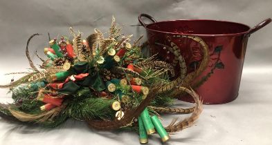 Christmas table centrepiece formed of faux pine foliage, pheasant feathers and gun cartridges