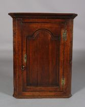 AN EARLY 19TH CENTURY OAK HANGING CORNER CUPBOARD, having a moulded cornice above a single door with