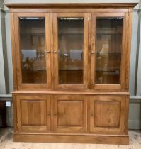 A fruitwood breakfront bookcase having three bevelled glazed doors above a base with three doors, on