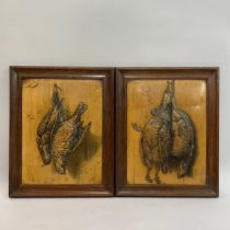 A pair of lacquered panels moulded in relief with hanging game, framed 31cm x 24cm