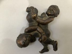 A 19th Century bronze scroll weight cast as a figure group of twin boys, 7cm x 5.5cm (at fault)