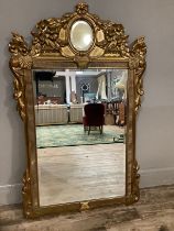 A gilt composite wall mirror having bevelled glass within a frame moulded with clams, a flower