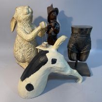 A rabbit holding a lantern, model of a terrier tunnelling, wood carving of a figure playing a flute,