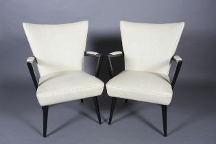 A pair of 1950s black framed cocktail lounge chairs upholstered in cream PVC