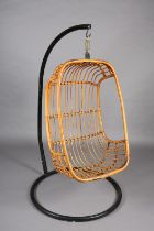 A rattan basket swing chair, pendant from a black metal tubular frame