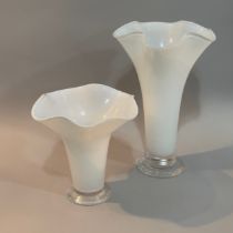 A pair of Orrefors white glass vases of graduated size with flared wavy rims on clear glass foot,