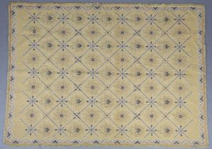 A mid century needlwork tapestry style rug with blue squares containing florettes on a mustard