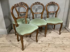 A set of four walnut continental style chairs with heavily carved and pierced back upholstered