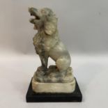 An alabaster carved figure of a poodle, mouth open upon plinth on ebonised base, 19cm high