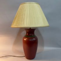 A ceramic vase-shaped table lamp finished in dark terracotta with green band, cream pleated silk
