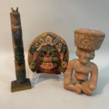 A Nepalese papier mache face mask painted in bright colours, a Mayan clay figure of a god seated and