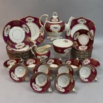 An English china tea service printed and enamelled with flowers within a gilt cartouche and a puce