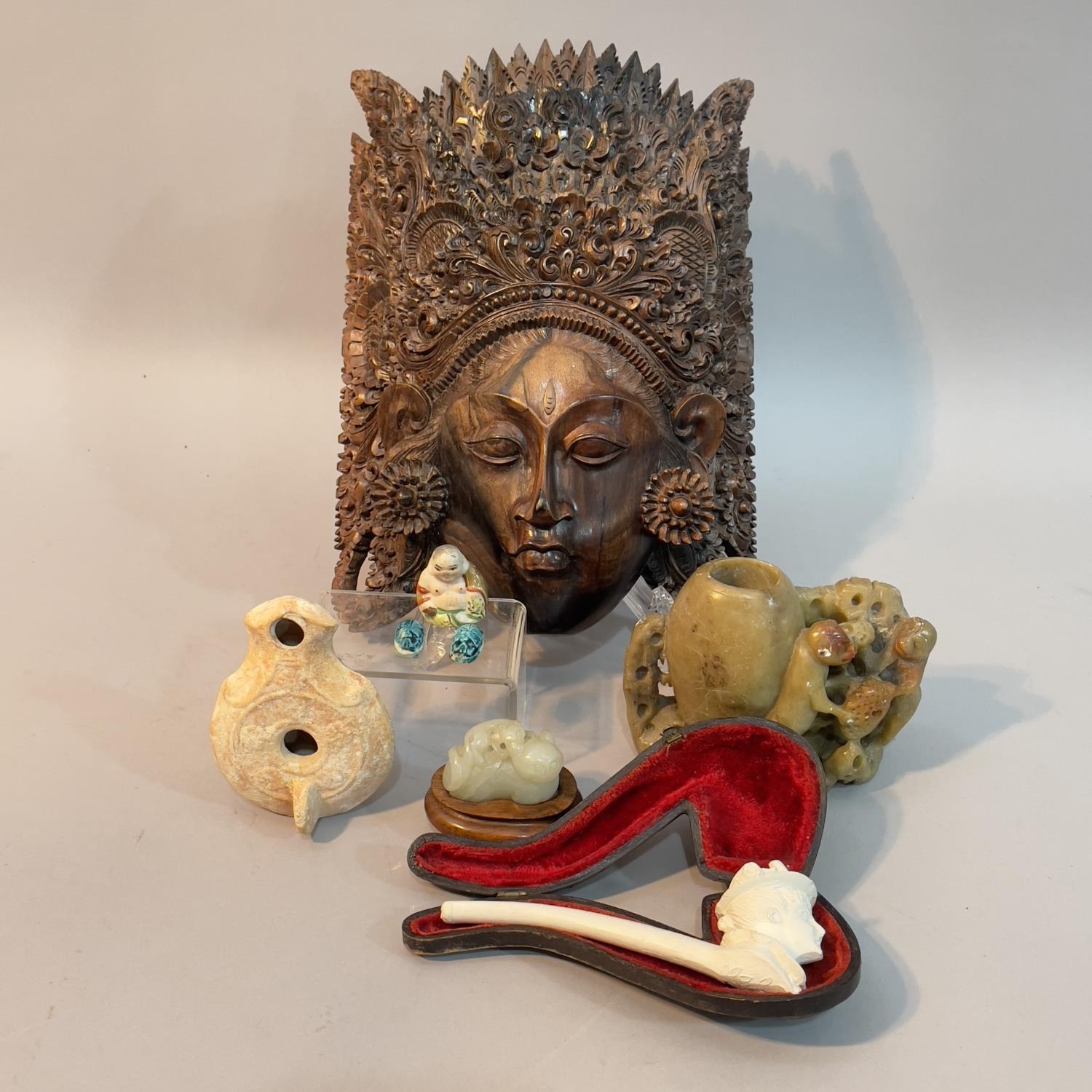 A Thai hardwood facemask with elaborately carved head dress together with a soapstone carved vase