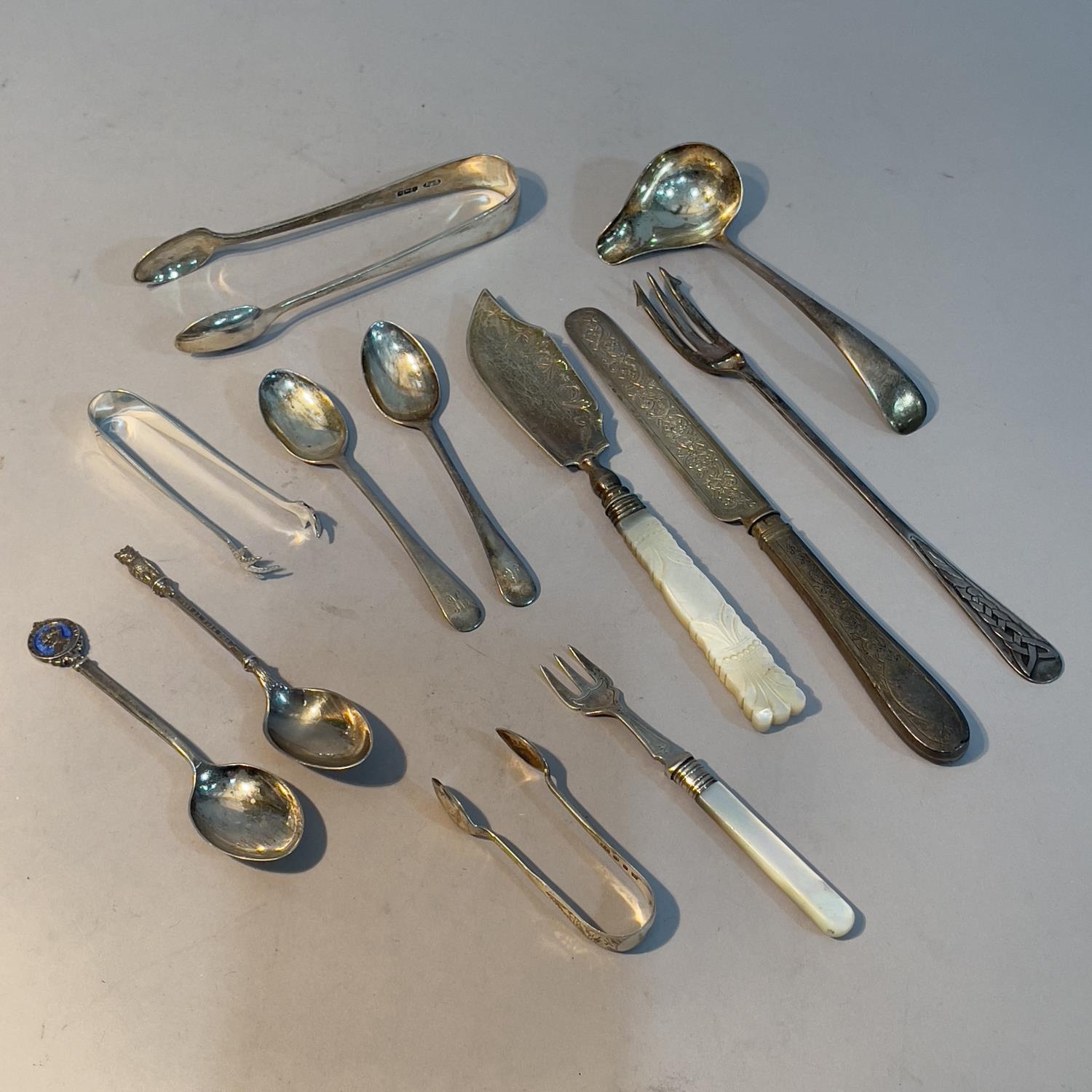 A collection of 19th and early 20th century silver spoons, pickle fork, sugar tongs etc