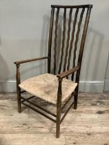 An Arts and Crafts style mahogany nursing chair with waved back on rush seat