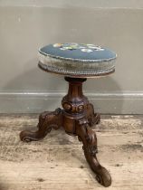 A Victorian mahogany music stool with adjustable seat upholstered in floral needlework