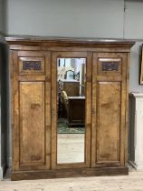 A Victorian walnut triple wardrobe with carved cartouches