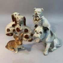 A pair of Staffordshire spaniels 15cm high, a continental bulldog holding a basket of puppies, a