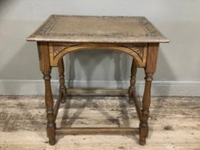 An oak side table, the top carved with oak leaves on turned legs with stretcher