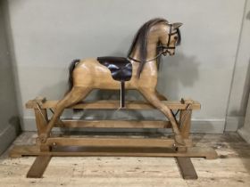 A fruitwood carved rocking horse with leather reigns and saddle with horse hair mane and tail, 163cm