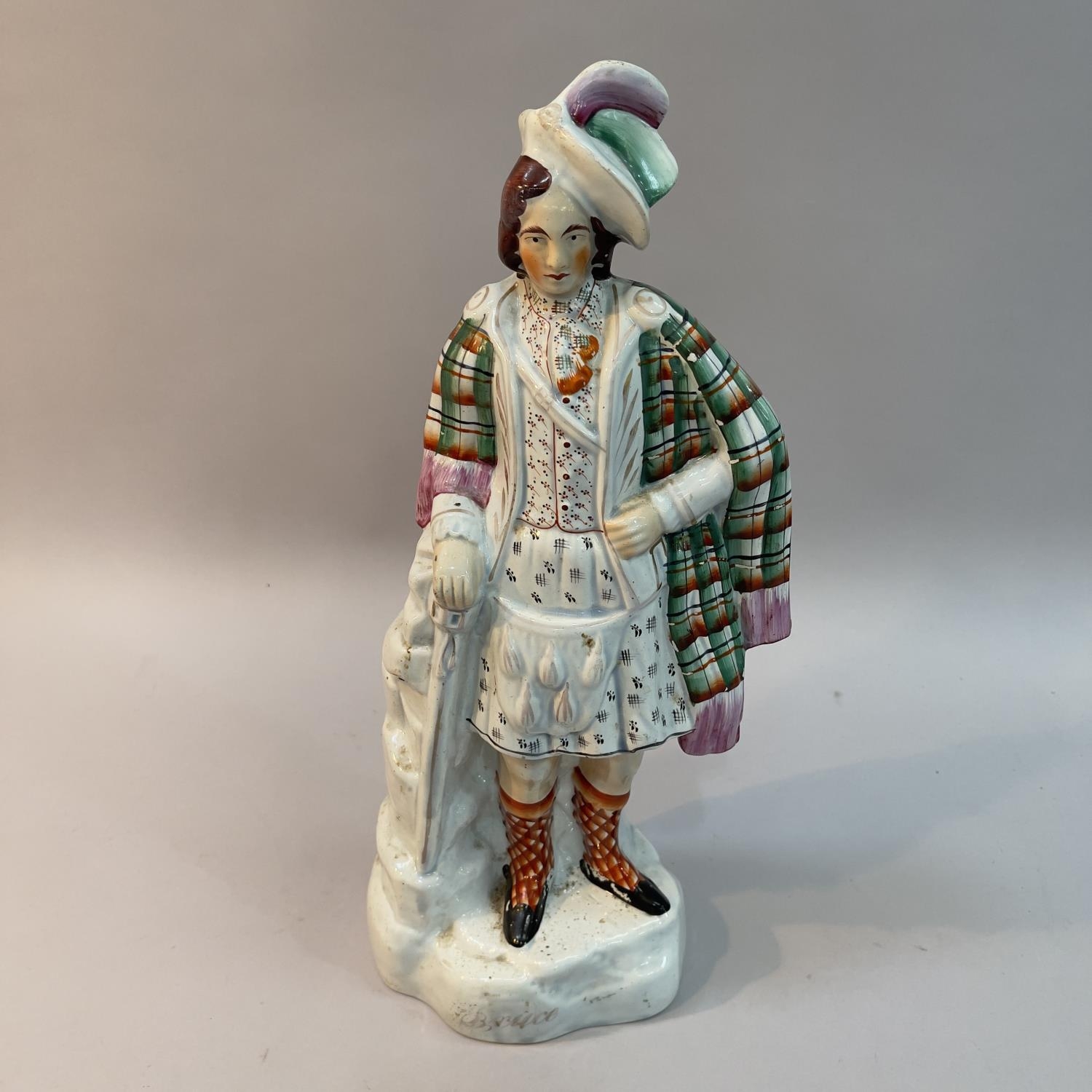 A mid 19th century Staffordshire pottery figure of Robert The Bruce standing wearing a feathered