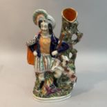 A mid 19th century Staffordshire pottery figural spill vase of a Scottish huntsman and hound, fallen