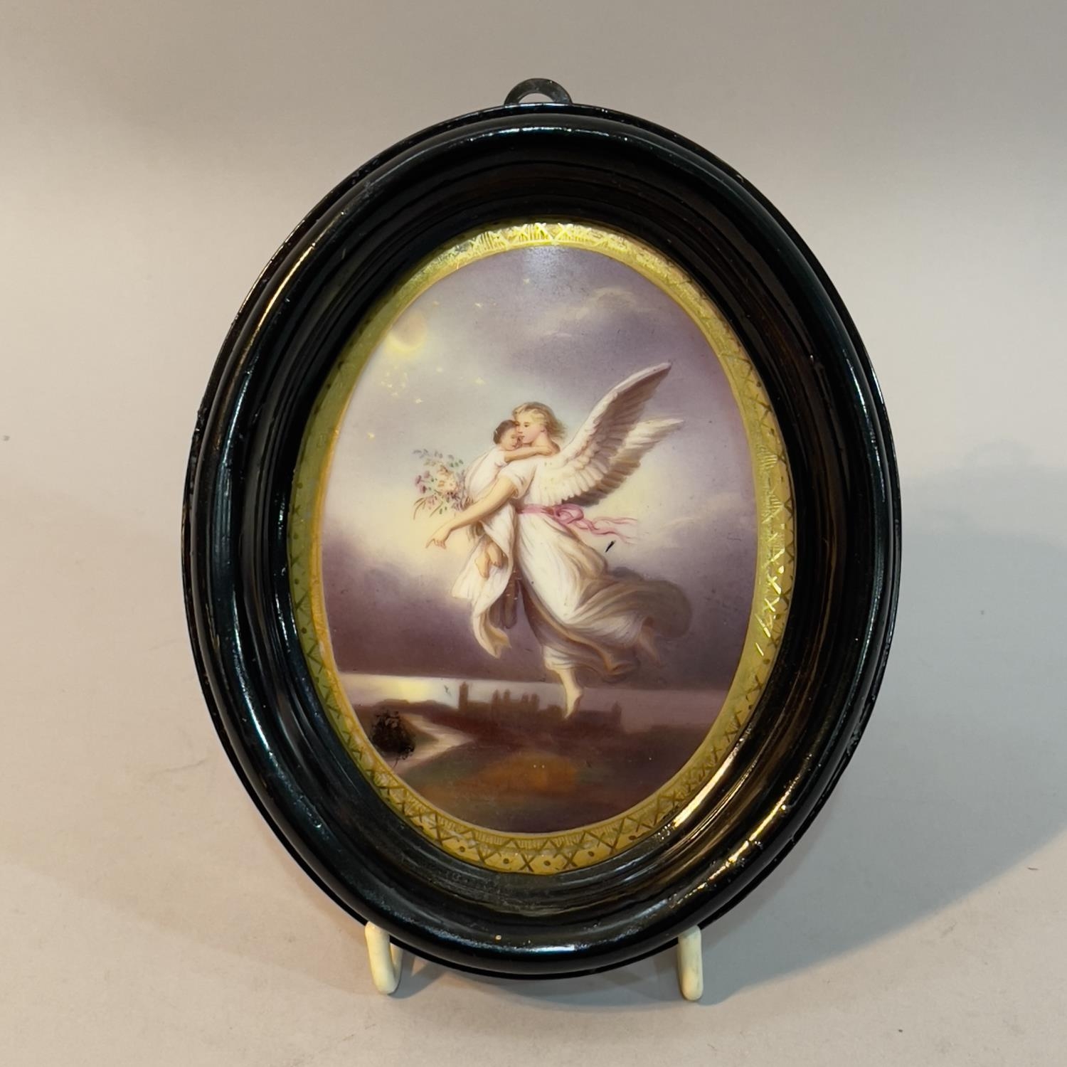 A printed and painted portrait miniature of an angel and child and ebonised frame, overall 14.5cm