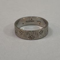 A diamond set band ring in 18ct. white gold. The small eight cut stones, star set to the textured